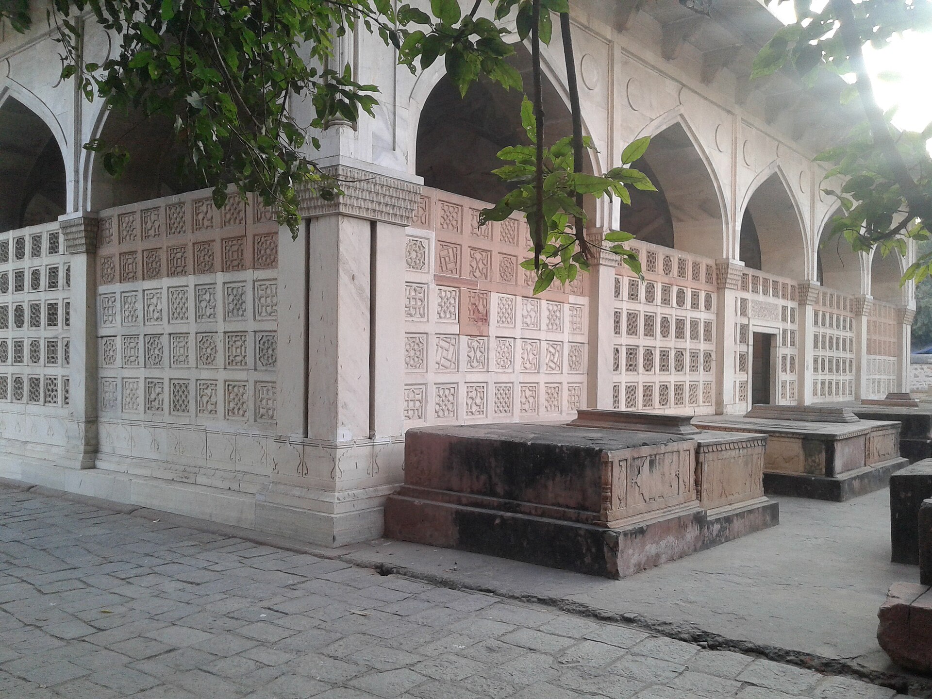 The exterior of Mirza Galib's tomb in Nizamuddin features intricate stonework and arched openings.